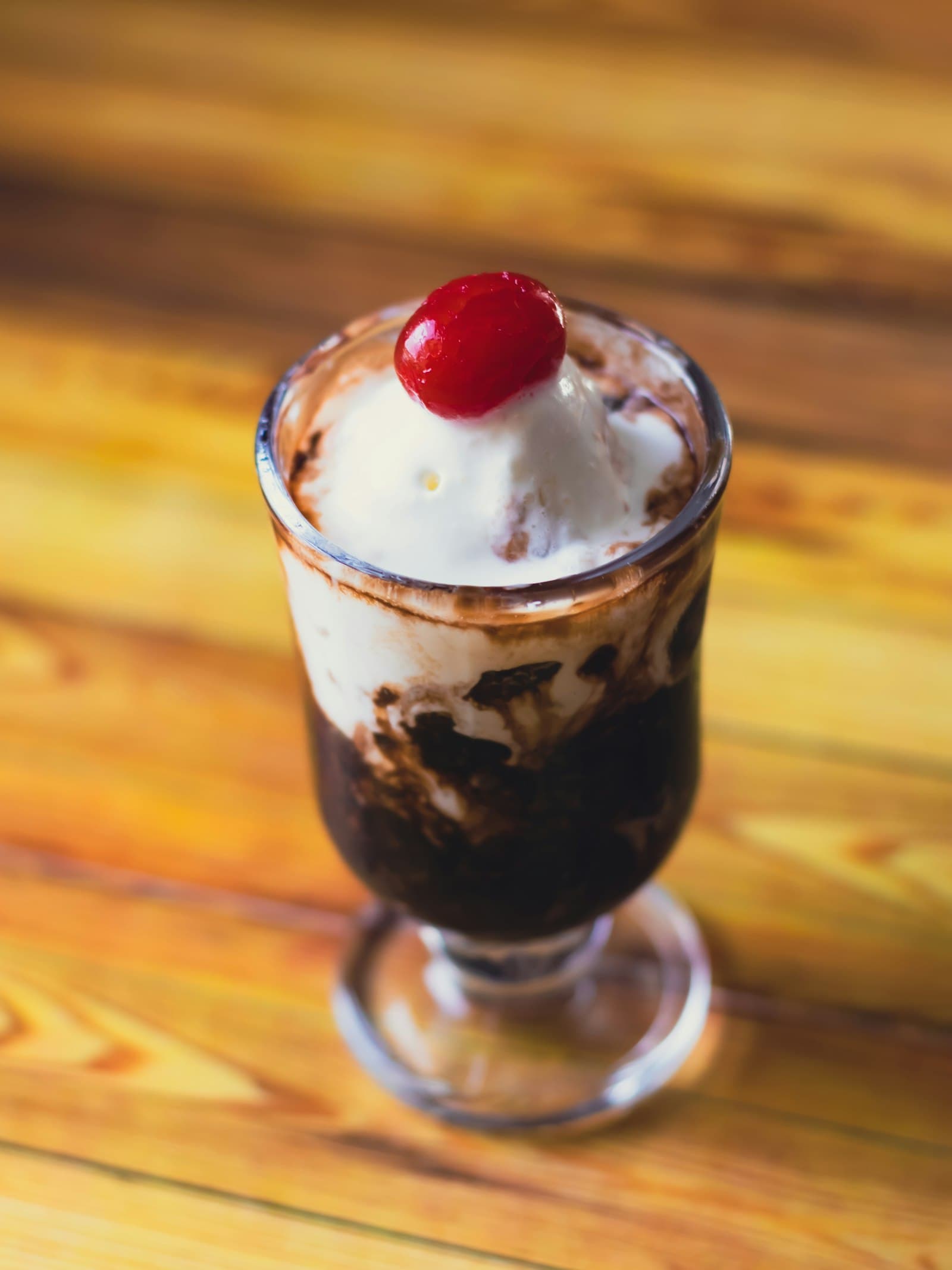 A tall glass of chocolate falooda topped with ice cream and a cherry