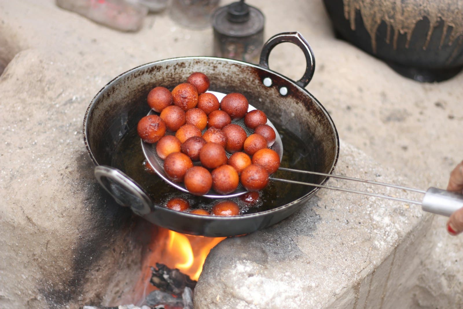 Gulab jamun dumplings frying golden in a pan
