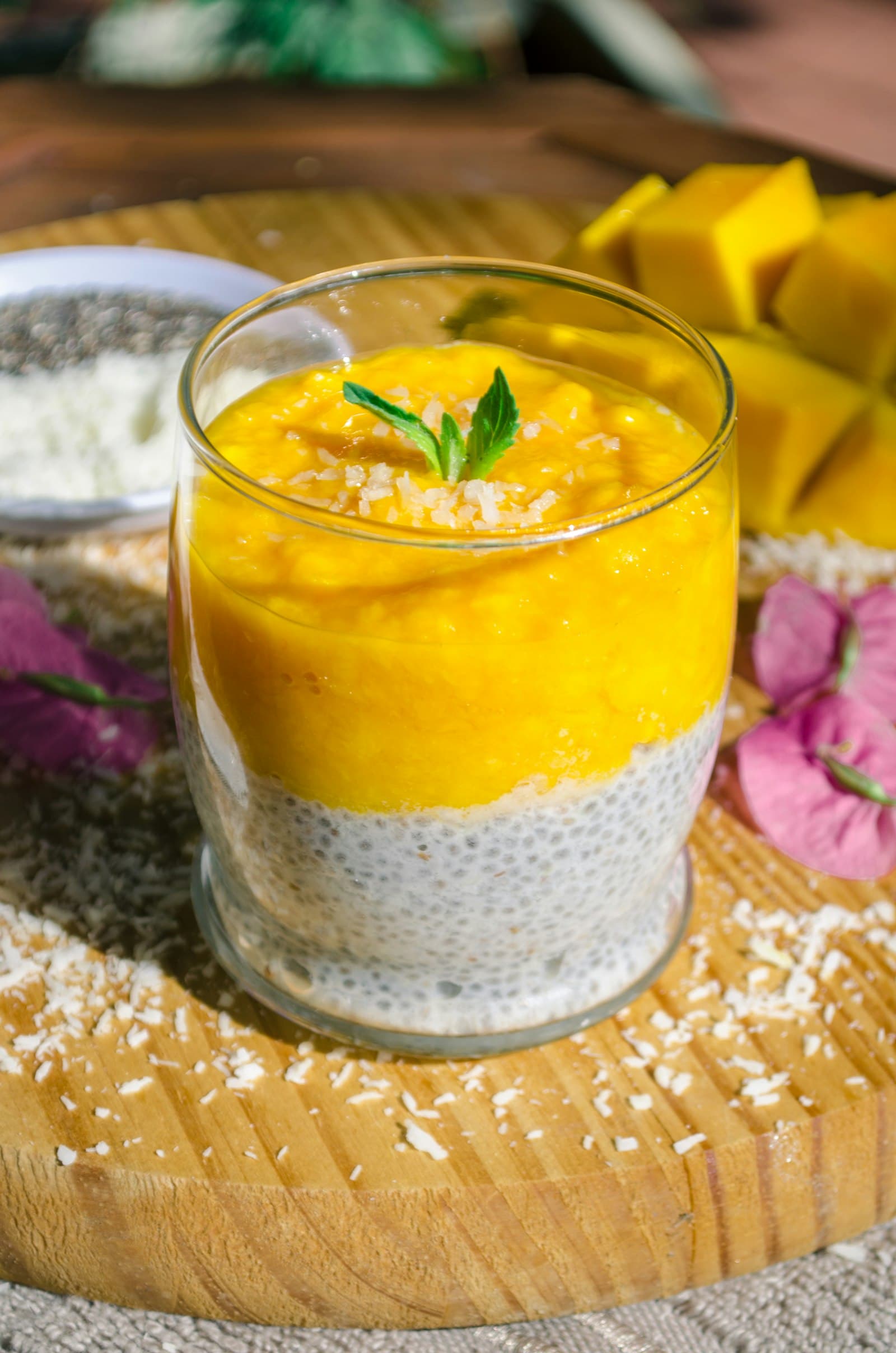 A glass of mango dessert layered over basil seeds, topped with mint